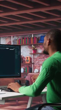 Dikey Video Afrikalı Amerikalı işçi, modern bir çatı katında fotoğrafları olan üretici yapay zeka programını kullanıyor. Genç adam derin öğrenme modelleri ile görsel içerik yaratıyor ve yapay zeka arayüzü ile monitörde istemlerde bulunuyor