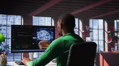 Siyah teknoloji mühendisi bir yapay zeka beyin ağını makine öğrenmesi için programlıyor, bakım yapıyor ve yazılım sistemlerinde hata ayıklama yapıyor. Teknisyen kodlama dili kullanır. Kamera B.