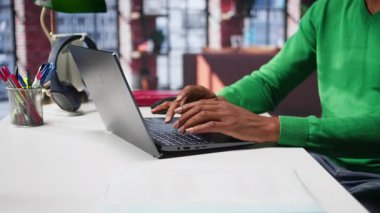 Freelancer, internet günlüğü için yazı içeriği hazırlıyor, dizüstü bilgisayarıyla hikaye anlatma üzerine çalışıyor. Siyahi adam sosyal medya paylaşımları yazıyor, birden fazla iş yapıyor. Kamera B.