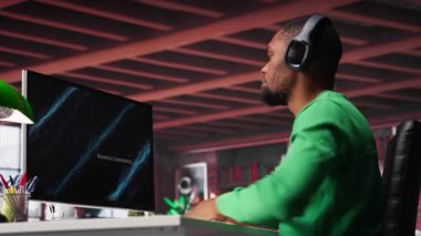 Ofiste telgraf işçisi PC 'deki iş konferansını izliyor, istatistik tablolarına bakıyor. Afrika kökenli Amerikalı uzaktan kumandalı bir çalışan bilgisayardaki sunum grafiklerine bakıyor. Kamera A.