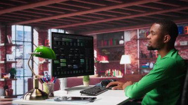 Afro-Amerikalı adam, evindeki yazılımda görsel programlama için terminal penceresindeki notlara bakıyor. Mühendis yazma ve test kodları tarafından kullanılan kodlama uygulaması. Kamera B.