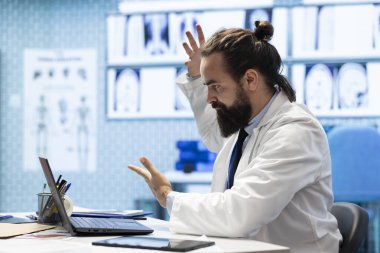 Endişeli doktor, hastalıkların önlenmesi için baskı altında çalışıyor, radyografi sonuçlarını ve sağlık kayıtlarını analiz ediyor. Doktor doğru tedavi planını ve tıbbi tesisi arıyor..