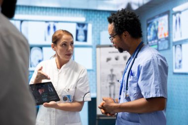 Doktorlar yeni tedavi planının röntgen ve tomografi sonuçlarını bir muayenehanede tartışırlar. Tanısal ve sağlık hizmetleri sağlamak için çalışan lisanslı uzmanlardan oluşan bir ekip, organların radyografisini inceliyor..