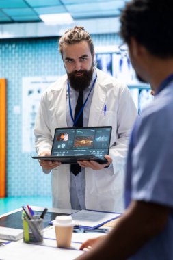 Nöroloji uzmanı MRI beyin taraması sonuçlarını doktorlarla birlikte inceleyerek hastalıkların önlenmesi için doğru tedavi planını tartışıyor. Lisanslı nörolog ve ekibi tomografiyi inceliyor..