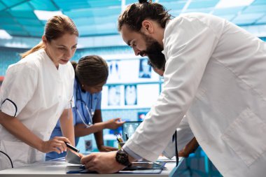 Radyologlar ve uzmanlar doğru tedavi planları için x ışını test sonuçlarını inceliyorlar. Bir grup lisanslı sağlık uzmanı sigorta hizmetleri için özel bir klinikte çalışıyorlar..