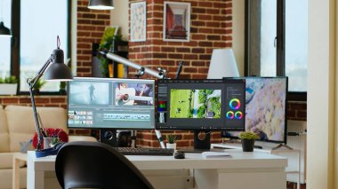 Medya üretimi ve video sonrası prodüksiyon için tasarlanmış bir oturma odasında temiz, modern bir masa düzeni. Çift monitörler video düzenleme yazılımını, teknik araçları ve renk çarkını gösterir. Profesyonel bir dokunuş ekleyin..