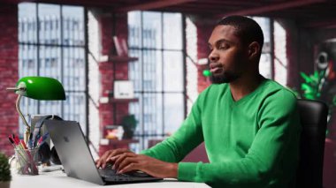 Afrika kökenli Amerikalı uzaktan kumandalı işçi, bilgisayardaki günlük serbest çalışma işlerini hallediyor, modern dairesinin rahatlığı için rahatça çalışıyor. Teknolojiden anlayan siyah adam internet kullanıcısı, birden fazla iş yapıyor. Kamera A.