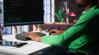 Erkek programcı bilgisayar üzerinde kod ve çalışan betik, programlama dili yazar. Yazılım içerisindeki hataları düzeltme konusunda Afrika kökenli Amerikan bilişim uzmanı yeni özellikler geliştiriyor. Kamera A.