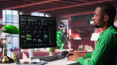 Afro-Amerikalı adam, evindeki yazılımda görsel programlama için terminal penceresindeki notlara bakıyor. Mühendis yazma ve test kodları tarafından kullanılan kodlama uygulaması. Kamera A.