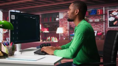 Çağdaş dairesinde yapay zeka sohbet yazılımını görüntülemek için mesaj kullanan siyahi bir adam. Dijital ekran nöral ağlar aracılığıyla üretken içeriği gösterir, öngörü modellerini ve görselleştirilmiş verileri geliştirir. Kamera B.