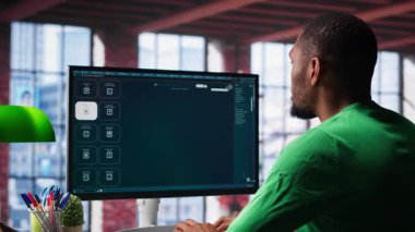Zenci adam, üretken bir ev ortamında mesajlardan video görüntüsü üretmek için derin öğrenme araçları kullanıyor. Freelancer üretken yapay zeka montajı için bilgisayar kullanır. Kamera A.