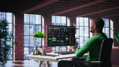 Afro-amerikan mühendis terminalin penceresinde görsel kodlama üzerinde çalışıyor, programlama dili yazıyor ve notları gözden geçiriyor. BT uzmanı hataları düzeltmek için hata ayıklama algoritmaları kullanıyor. Kamera B.