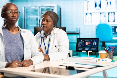 Afrika kökenli Amerikalı kadın doktor steteskopla solunum danışmanlığı yapıyor. Kalp atışlarını ve akciğerlerinin normal çalışmasını dinliyor. Doktor nabzını kontrol ediyor..