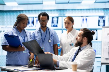 Modern bir özel klinikte teşhis verilerini analiz eden ve tedaviyi planlayan bir grup sağlık çalışanı, işbirliğini vurguladı. Kurtarma planlarının koordine edilmesi ve son test sonuçlarının tartışılması.