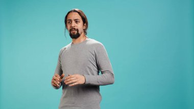 Yüzünü ellerle örten korkmuş bir adamın portresi stüdyo arka planında izole bir şekilde duruyor. Korkmuş yüz ifadesi olan korkmuş kişi şoka uğruyor, perişan hissediyor, kamera B