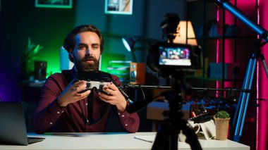 İzleyiciler için inceleyen bir adamın tuttuğu fütüristik VR gözlüklerini yakın plan çek. Alet meraklıları için internet yıldızı çekim kanalı vlog sanal gerçeklik kulaklığı, kamera A