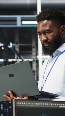 Dikey Veri Merkezi Sistem Yöneticisi, düğüm ağacı araçları kullanarak altyapı sorunlarını analiz ediyor. Sunucu merkezindeki adam, sistem sağlığını optimize etmek için yapay zeka görselleme bilgilerini kullanıyor, kamera B