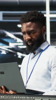 Neşeli veri merkezi mühendisinin dikey video portresi düğüm ağacı araçları kullanarak vites sorunlarını analiz ediyor. Sistemi optimize etmek için yapay zeka görselleştirme bilgilerini kullanan neşeli Afrika kökenli Amerikan sunucu merkezi uzmanı