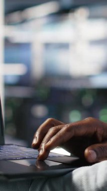 Yapay zeka veri analizi grafiklerini yorumlamak için laptop kullanan veri merkezi çalışanının dikey videosu. Sunucu odası teknisyeni, sistem ölçümlerinde yapay zeka kullanıyor.