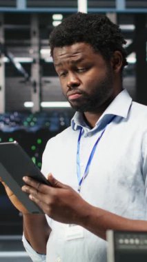 Yapay zeka veri analizi grafiklerini yorumlamak için tablet kullanan dikey video veri merkezi mühendisi. Sunucu odası çalışanı yapay zeka kullanarak sistem performans öngörüsü ölçümleri yapıyor