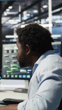 Tekerlekli sandalyedeki dikey video veri merkezi mühendisi ve meslektaşı düğüm ağacı programlama aracı kullanarak otomatik görevleri denetliyor. Özel sunucu tarım ekibi, yapay zeka analizlerine dayalı sistem ayarlarını ayarlar