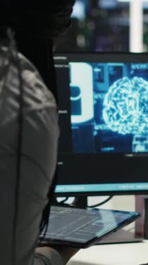 Tekerlekli sandalyedeki dikey video veri merkezi mühendisi ve meslektaşı düğüm ağacı programlama aracı kullanarak otomatik görevleri denetliyor. Özel sunucu tarım ekibi, yapay zeka analizlerine dayalı sistem ayarlarını ayarlar