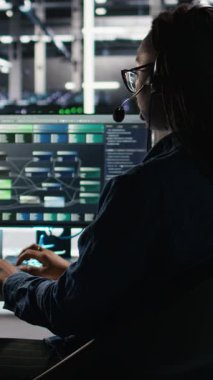 Dikey Veri Merkezi çalışanı, ses kulaklığı ve görsel programlama panelini müşterinin bildirdiği sorunları gidermek için kullanır. Sunucu çiftliği teknisyeni düğüm ağaç arayüzüne bakıyor, konuşuyor