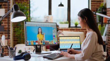 Asyalı grafik tasarımcısı iyi düzenlenmiş bir ev çalışma alanında fotoğraf rötuşlaması için düzenleme yazılımı kullanır. Kadın serbest yazar, yaratıcı bir sanat kariyeri için gerekli dijital aletleri kullanır. Kamera B.