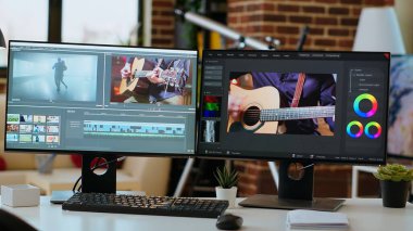 Oturma odasında boş bir masa var. İkili monitörlerde bir video projesi, video yapımı var. Ortam oluşturma için yazılım ve teknoloji araçları ile uzak çalışma için optimize ofis ayarları.