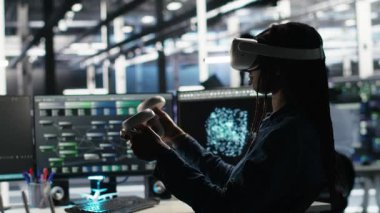 Veri merkezi mühendisi sanal gerçeklik teknolojisi ve düğüm ağacı yazılımını kullanarak veri tabanlarını analiz ediyor. Dişli performansını artırmak için görsel programlama araçları ve VR teçhizatı kullanan sunucu odası çalışanı