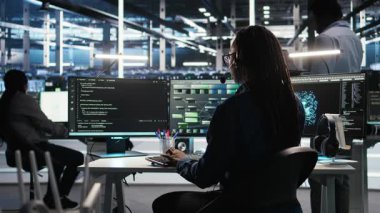 Veri merkezi uzmanı düğüm ağacı arayüzünü inceleyerek teknik destek sağlıyor. Sunucu odası teknisyeni iş arkadaşlarıyla mikrofonla konuşuyor, görsel programlama yazılımı kullanıyor, kamera A