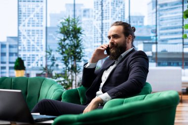 CEO, dizüstü bilgisayarındaki mali raporları incelerken yatırımcılarla önemli bir telefon görüşmesi yapıyor ve yönetiyor. İş yerinde iş hayatında stratejik karar alma.