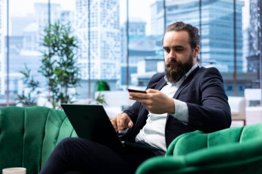 Girişimci kredi kartı ve bilgisayarını kullanarak para transferi yapıyor, başarılı olmak için finansal konuları etkili bir şekilde ele alıyor. Erkek CEO son teslim tarihinden önce tüm ödemelerini yönetiyor..