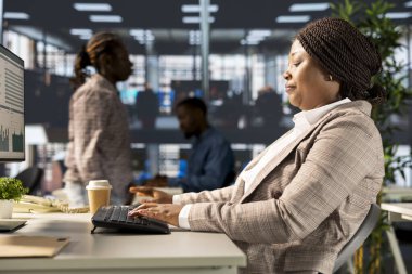 Afrika kökenli Amerikalı kadın yönetici iş operasyonlarına odaklandı, ilerleme sağlamak ve hedeflere ulaşmak için bir proje özetini gözden geçirdi. Çözümler ve kaynak tahsis planları aranıyor.