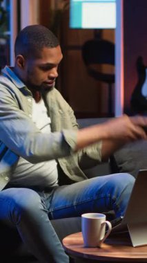 Dikey Video Afrikalı Amerikalı serbest yazar dizüstü bilgisayardaki bir web kursuna katılarak yeteneklerini geliştirmek için bir tartışmaya katılıyor. Erkek adam evde oturup sohbet ederek buğday biti dersinden zevk alıyor.