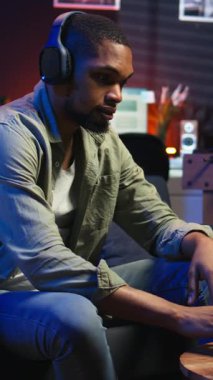 Dikey Video Afrikalı Amerikalı serbest yazar dizüstü bilgisayardaki bir web kursuna katılarak yeteneklerini geliştirmek için bir tartışmaya katılıyor. Erkek adam evde oturup sohbet ederek buğday biti dersinden zevk alıyor.