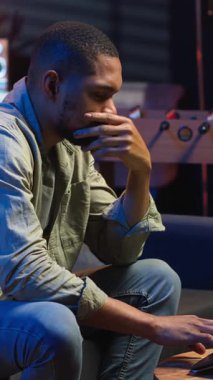 Dikey video yorgun siyah adam bazı görevlerde başarısız oluyor ve evde odaklanmaya çalışıyor, fazla mesai yaptıktan sonra bitkinlikle uğraşıyor. Çok çalışan yorgun insan dizüstü bilgisayarı kapatır ve mola verir. Kamera B.