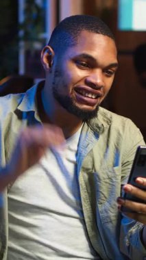 Dikey Video Afrikalı Amerikalı tele-işçi video konferansında iş arkadaşını arayıp not alıyor, yeni fikirler yazıyor ve oturma odasında internet üzerinden bilgi alışverişinde bulunuyor. Ders kitabı verileri. Kamera B.