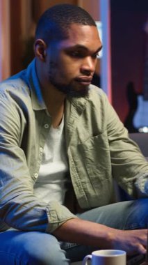 Dik Videolu Genç Yetişkin, kanepede oturup araştırma kağıtlarını analitikle okuyor, evdeki dosya ve belgelerle birden fazla iş yapıyor. İnsan profesyonel ya da kişisel gelişim konularına dalıyor