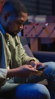 Dikey Video Siyah Serbest Çalışan kanepede oturuyor ve araştırma yapmak için bazı gazeteler okuyor, oturma odasında arşivlerle birden fazla iş yapıyor. Yetişkin dalışı profesyonel ya da kişisel gelişim konuları