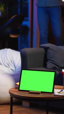 Dikey Video Afrikalı Amerikalı erkek serbest zaman geçirmeyi seviyor. Fasulye torbasında kroma anahtarının yanında, kulaklıklı bir podcast izlemek için cihaz kullanıyor. Genç adam oturma odasında uzaktan dinleniyor.