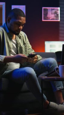 Dikey Video Siyah Serbest Çalışan kanepede oturuyor ve araştırma yapmak için bazı gazeteler okuyor, oturma odasında arşivlerle birden fazla iş yapıyor. Yetişkin dalışı profesyonel ya da kişisel gelişim konuları