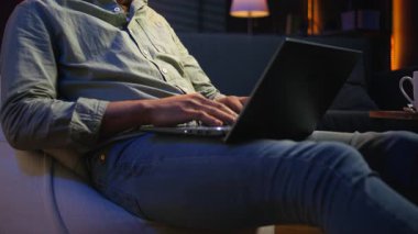 Afro-Amerikan yetişkin portresi evdeki bilgisayarında veri yazarken, bir fasulye torbasında rahatlarken. Uzaktan kumandalı bağımsız işlerde çalışan genç bir adam, sıradan bir tele-işçi. Kamera A.