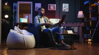 Erkek serbest çalışan, evde çalışan, kulaklıkla müzik çalan, en sevdiği şarkıları dinleyen ve uzaktan kumandalı çalışmalarına dikkat eden biri. Afrikalı Amerikalı adam programdan hoşlanıyor. Kamera A.