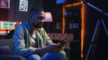 Kaygısız serbest çalışan arkadaşlarıyla telefonda mesajlaşan, koltukta oturan ve sosyal medya uygulamalarını kaydıran biri. Zenci adam uzaktan çalışırken eğlendirici olarak sergileniyor. Kamera A.