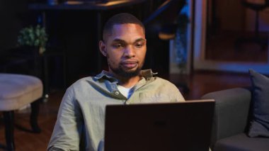 Siyah erkek serbest çalışan evden yeni beceriler öğrenmek için online kursa katılıyor, çevrimiçi video görüşmelerine katılıyor ve tavan arasından ders seyrediyor. Genç adam sanal eğitim sınıfına katılıyor. Kamera B.