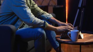 İnternette gezinen, müzik dinleyen, kulaklıktaki şarkılarla eğlenen ve görevleri tamamlayan serbest çalışan bir adam. Afro-Amerikalı adam kanepede uzanıyor ve oturma odasında dinleniyor. Kamera B.