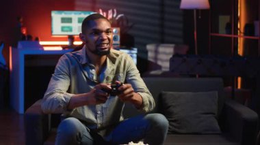 Afrikalı Amerikalı kızgın oyuncu, kaybettiği rakibi yüzünden hayal kırıklığına uğruyor. Oturma odasında bilgisayar oyunları turnuvasını kaybediyor. Oyun hatalarıyla sinirli bir insan. Kamera B.