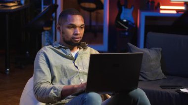 Siyah adam evde akıllı telefonunu kaydırarak işe ara veriyor, sosyal medyada arkadaşlarına mesaj atıyor ve eğleniyor. Neon ışıkları olan şık bir oturma odasında dinlenen adam. Kamera B.