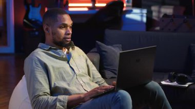 Siyahi adam internet dersine ev ortamından yeni beceriler geliştirmek için katılıyor, web konferansına katılıyor ve tavan arasından konferans seyrediyor. Sanal eğitim sınıfına katılan biri. Kamera B.